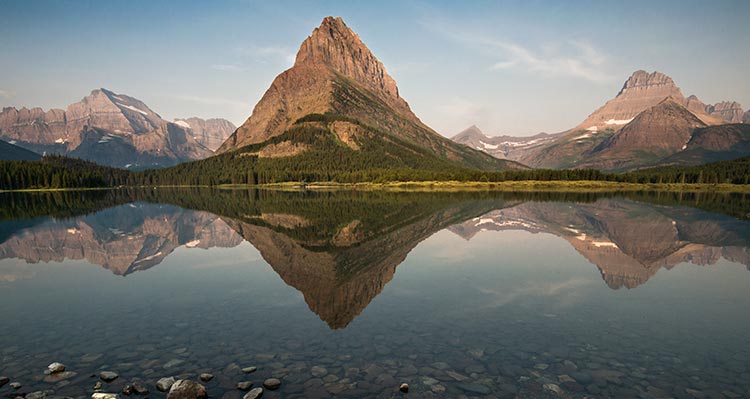 A tall triangular mountain across a small lake.