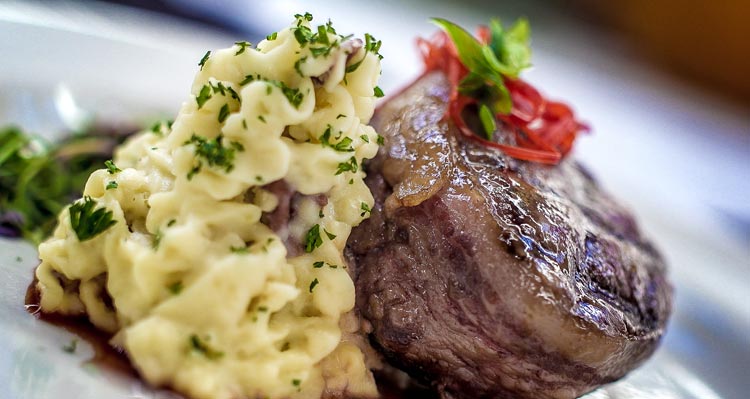 A close view of a steak and mashed potatoes.