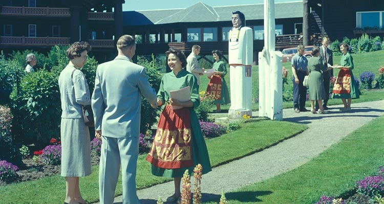 Groups of guests are greeted at a hotel on a lawn.