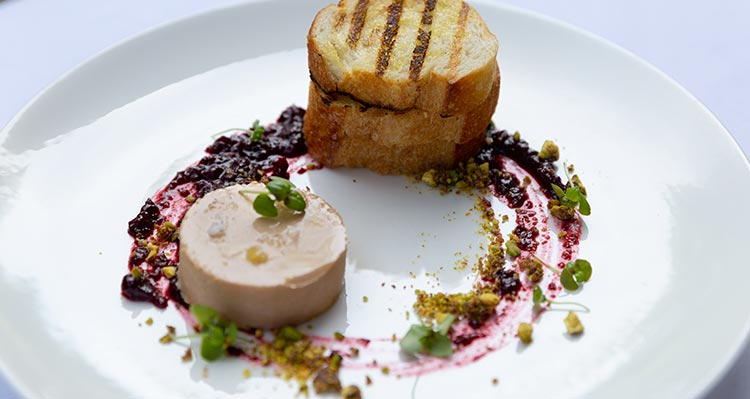 A finished plate of pate, toasted bread with jam garnish