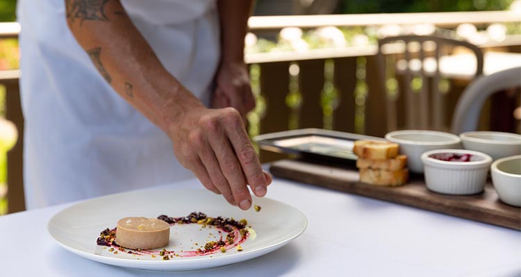 A chef puts the finishing touches on a plate of pate.