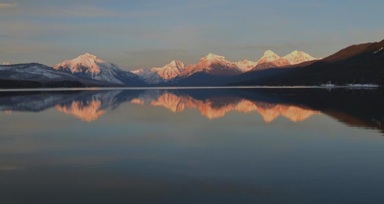 Snow-capped mountains across a shimmering lake