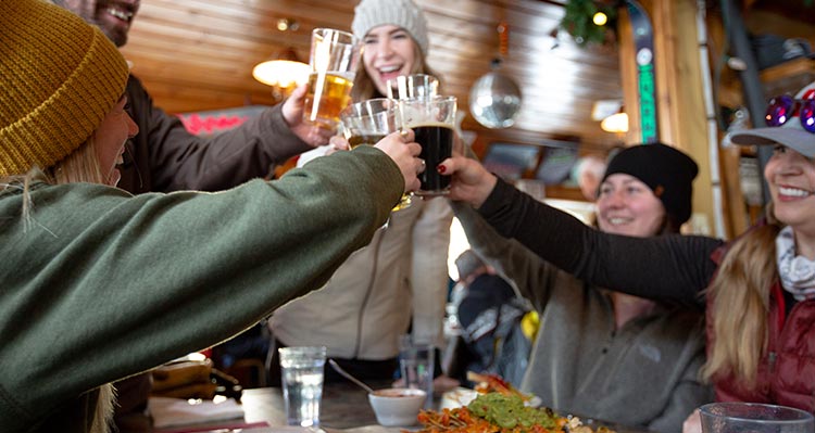 A group of friends raise their beers in a cheers.