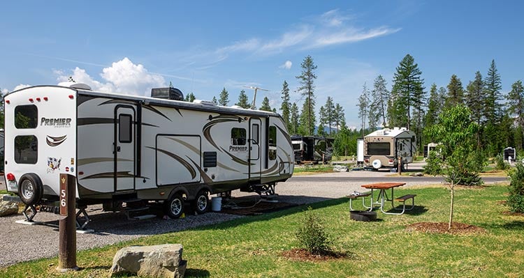 A camping trailer set in an RV park around trees.