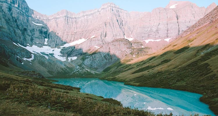 A view above a blue lake below high rocky mountains.
