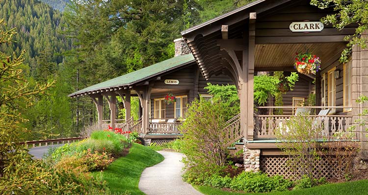 Two wooden cabins below some conifer trees.