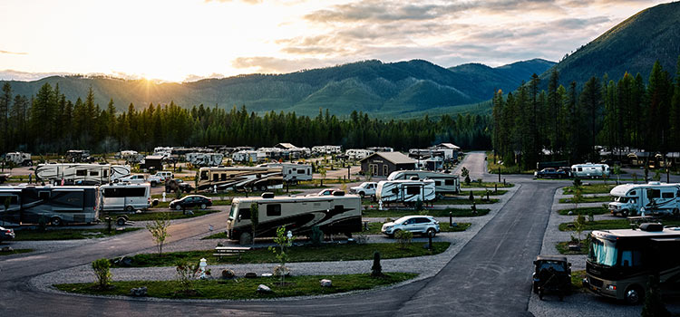 a view of an RV park at sunset with mountains in the background