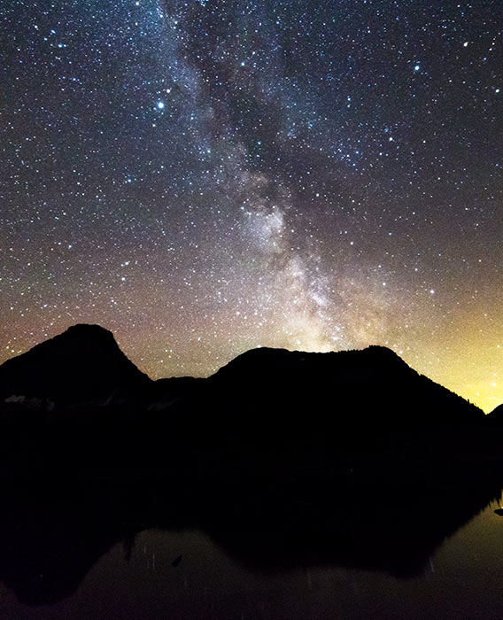 A landscape view of mountains with a night sky filled with stars and the milky way