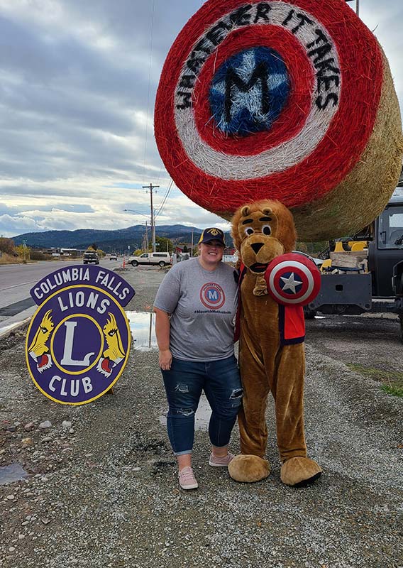 A woman stands with a lion mascot.