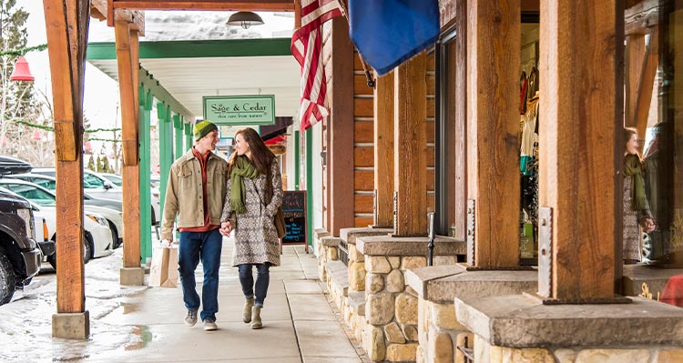 Two people walk down a small town sidewalk.