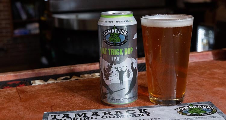 A beer and tall can on a table.