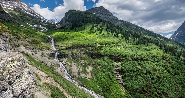 Mountains and green landscape with a waterfall flowing in between