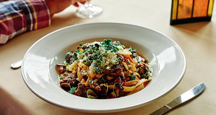 A diner plate filled with pasta topped with vegetables.