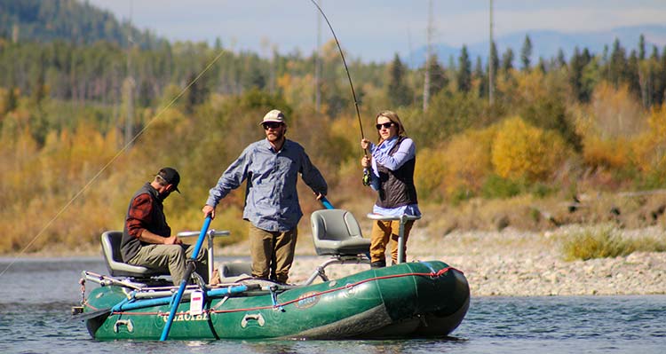 A group of three stand on a fishing boat with rods