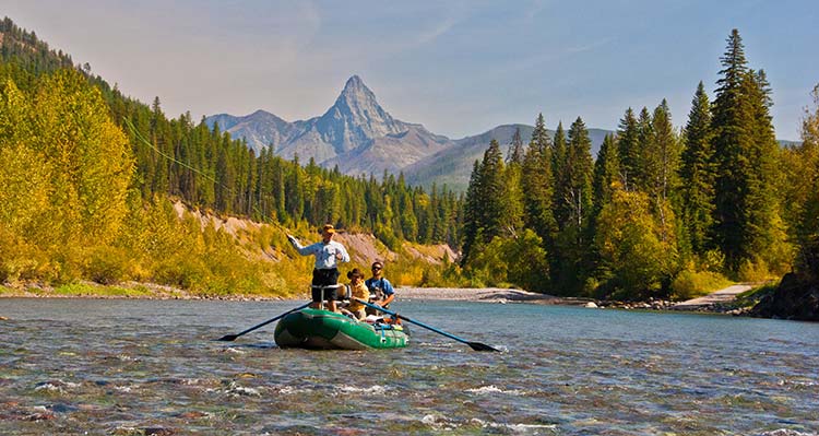 A group fish on a small boat with a mountain range in the background