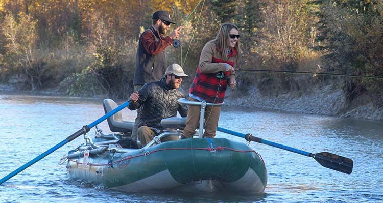 A group of adults look over the side of their fishing boat to the water.