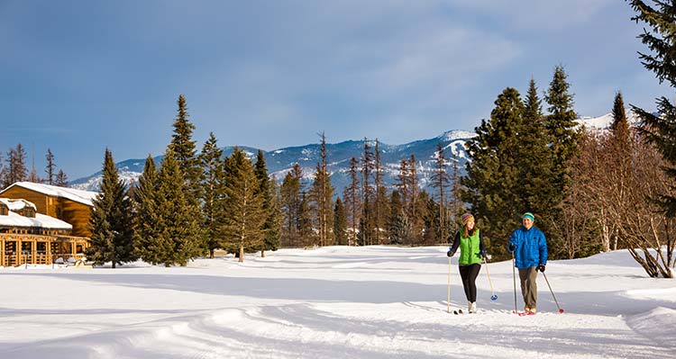 Two people cross country ski in the snow