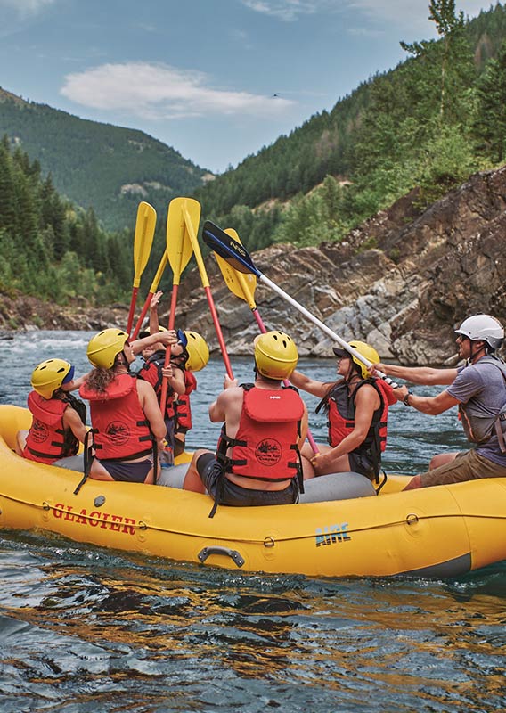 A group of rafters lift their paddles out of the water and tap together.