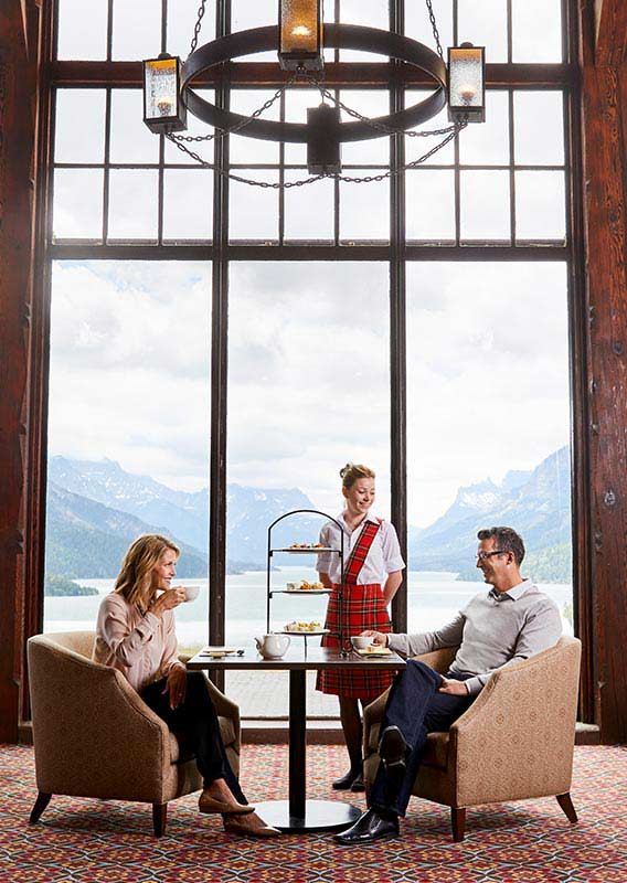 A couple sitting for Afternoon Tea overlooking Upper Waterton Lake