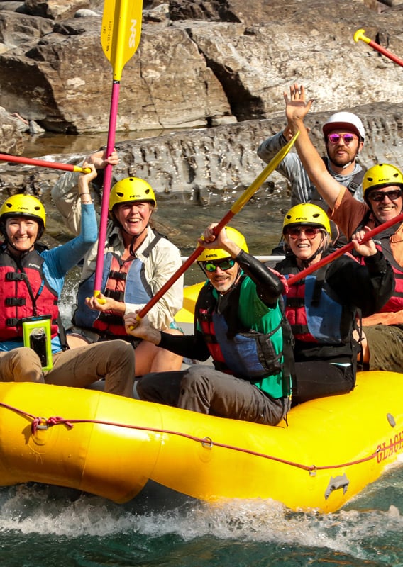 A rafting group cheering while they travel through river rapids