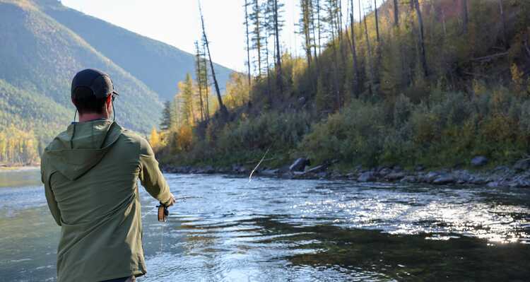 A man casts a fishing line in a river.