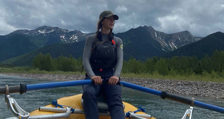 Rafting guide Brook sitting in a boat holding the rowing handles.