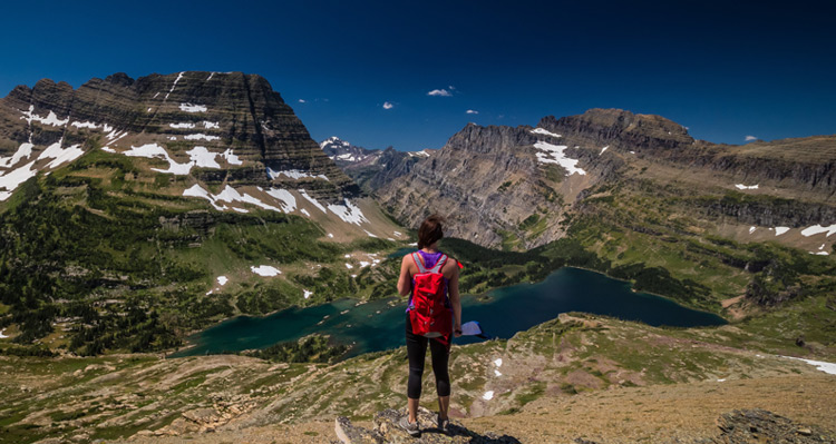 A person standing at the Continental Divide, looking at Hidden Lake in Glacier National Park.