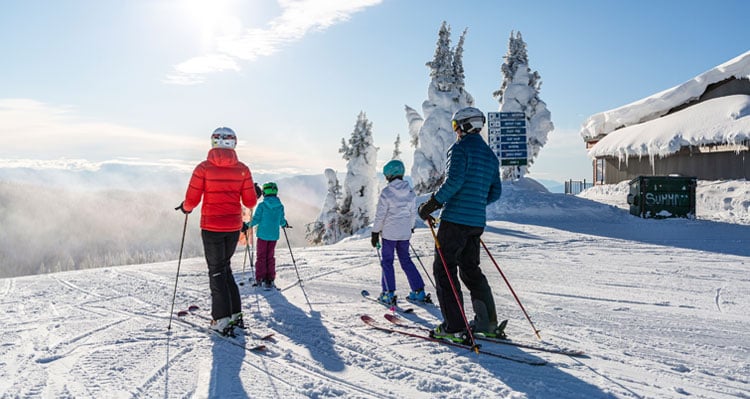 A family on skis at the stop of the run on the mountain