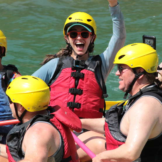 A close up photo of a rafting group with one of the members smiling and waving.