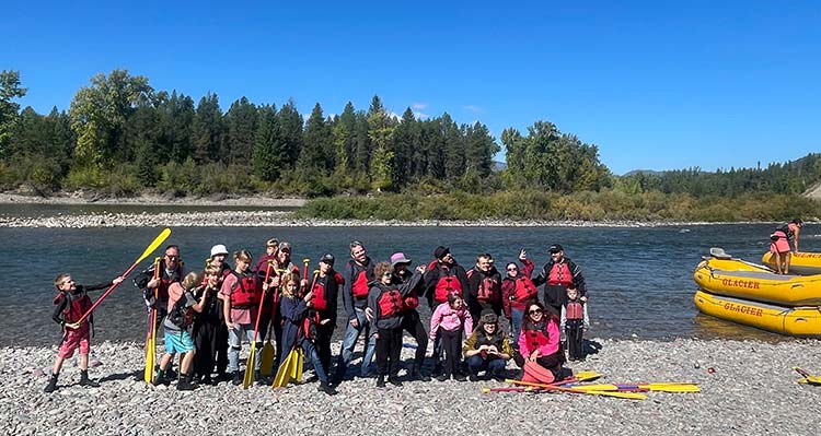 A group from Week of Hope poses at the riverside after rafting.