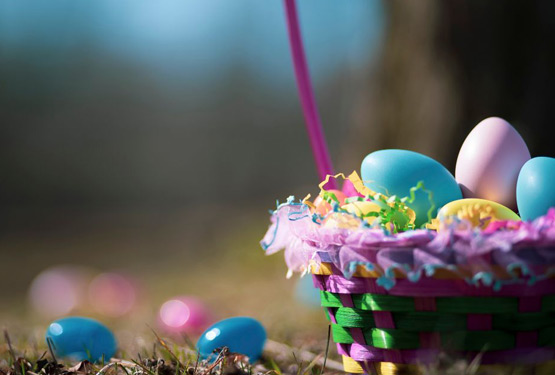 A close up photo of a basket with Easter eggs inside and scattered around.