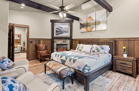 A lodge bedroom with a fireplace in the corner.