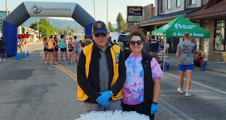 Volunteers stand at a hydration station at the end of a marathon run.