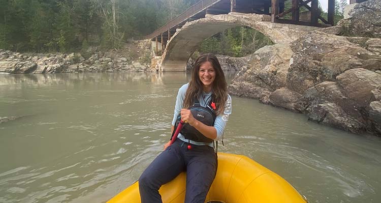 Rafting river guide, Brook, sits in a rafting boat.