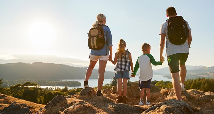 A family stands at a viewpoint looking out at a lake.