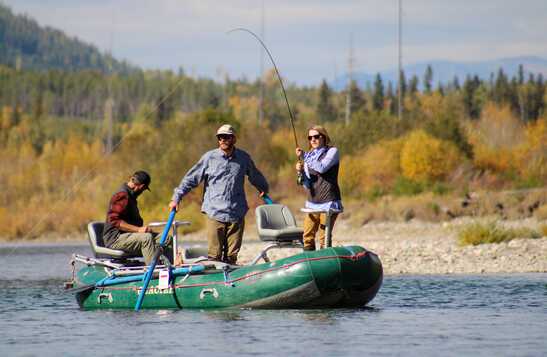 Guide with guests fishing on the river from the raft
