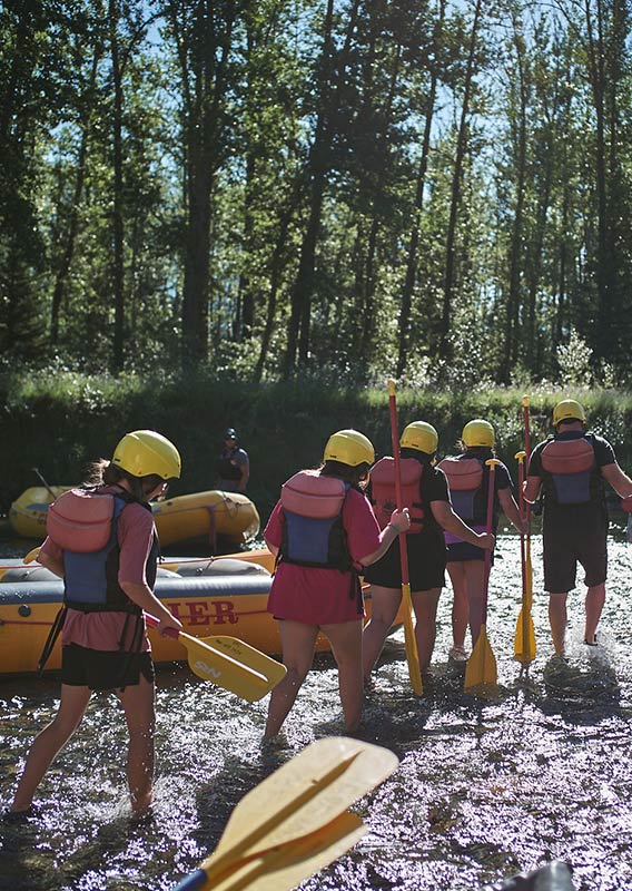 A group of rafters walk with their gear to a raft launch.