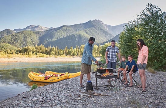A family and their rafting guide having a BBQ on the beach