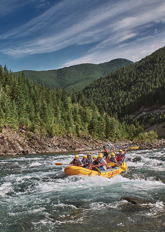 People cheer with their paddles on a rafting boat.
