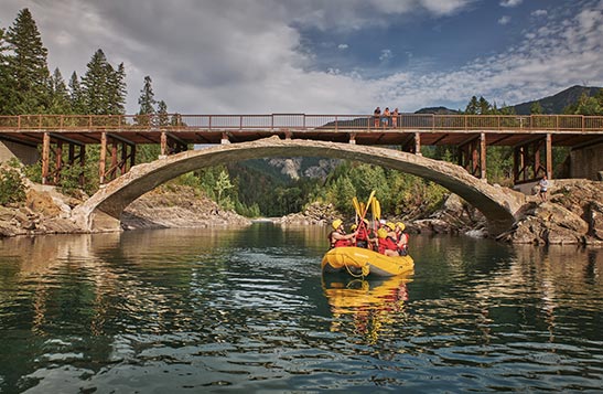 A river raft passes underneath an old bridge.
