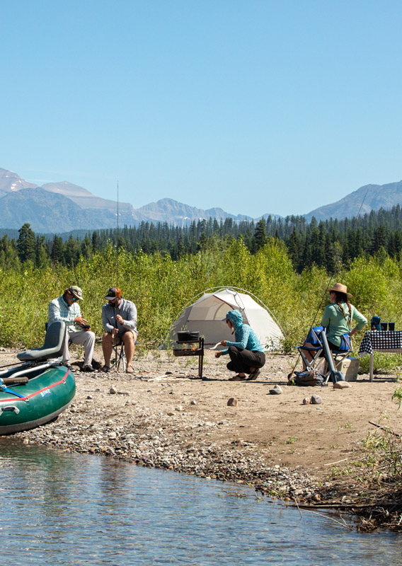 A group of people camping on a beach by the river