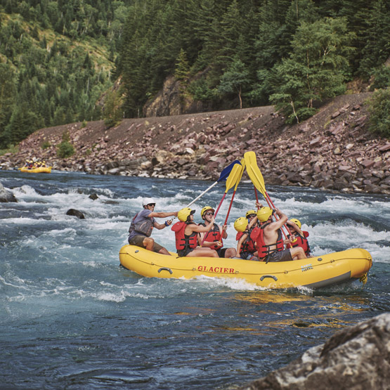 A rafting group raising their oars in the air, while floating down the Flathead River.