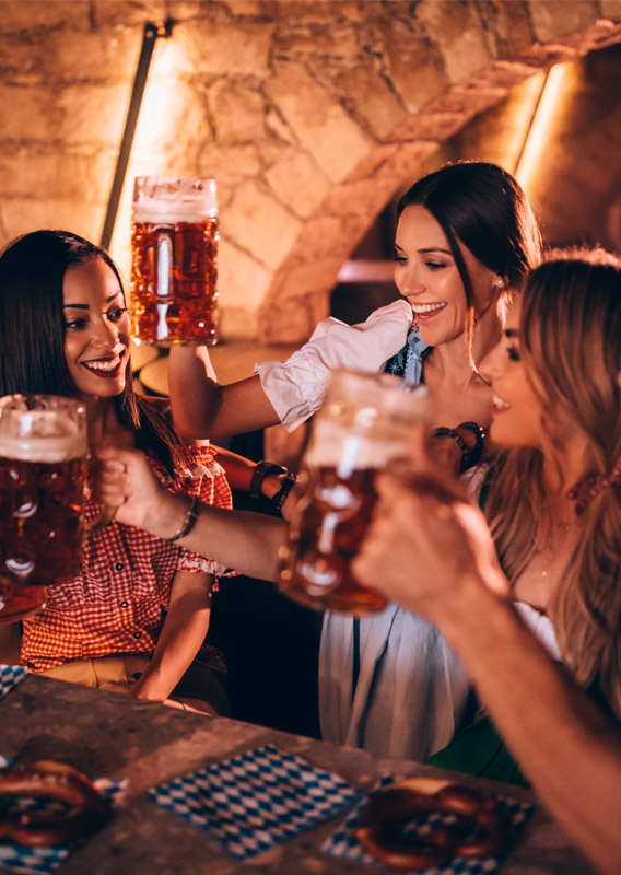 A group of people seated at a table, raising their steins of beer during a celebration.