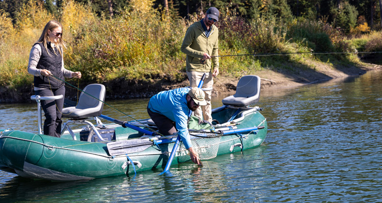 A fishing guide and guests releasing a caught fish back to the Flathead River in Glacier National Park.