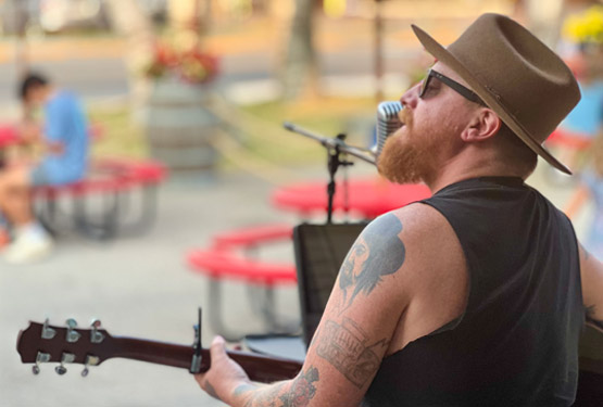 Kenny Bowling playing an acoustic guitar on stage.