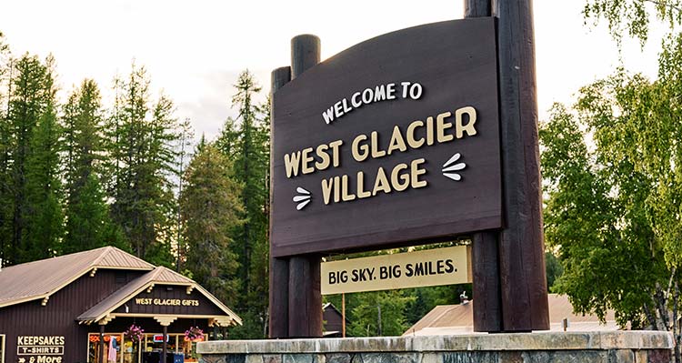 A large sign outdoors that says Welcome to West Glacier Village.