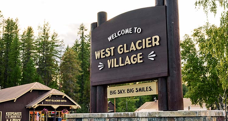 A large sign outdoors that says Welcome to West Glacier Village.