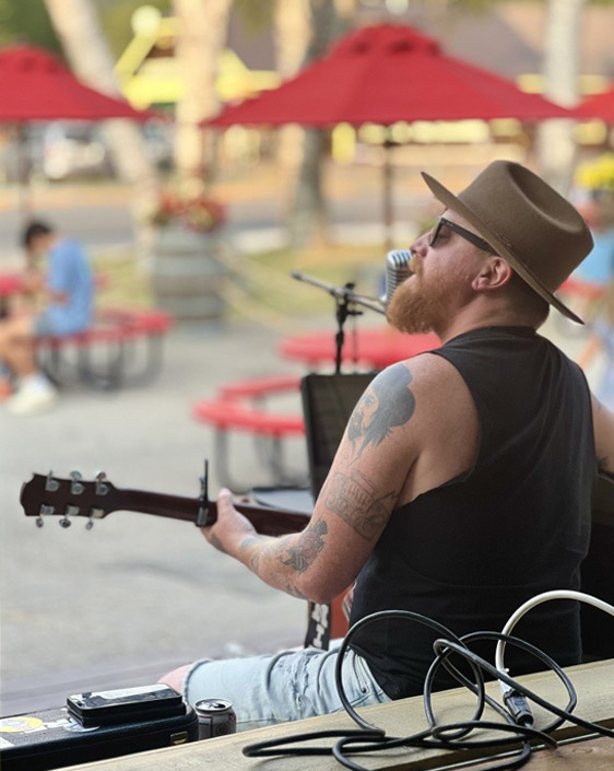 A person sitting on a bench, playing guitar.