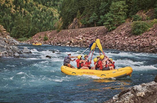 Rafters on a boat touch the tips of their paddles together.
