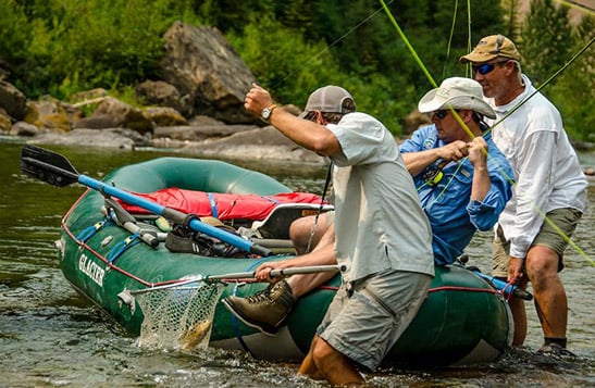 A group reeling in a fish from a raft on the Flathead River
